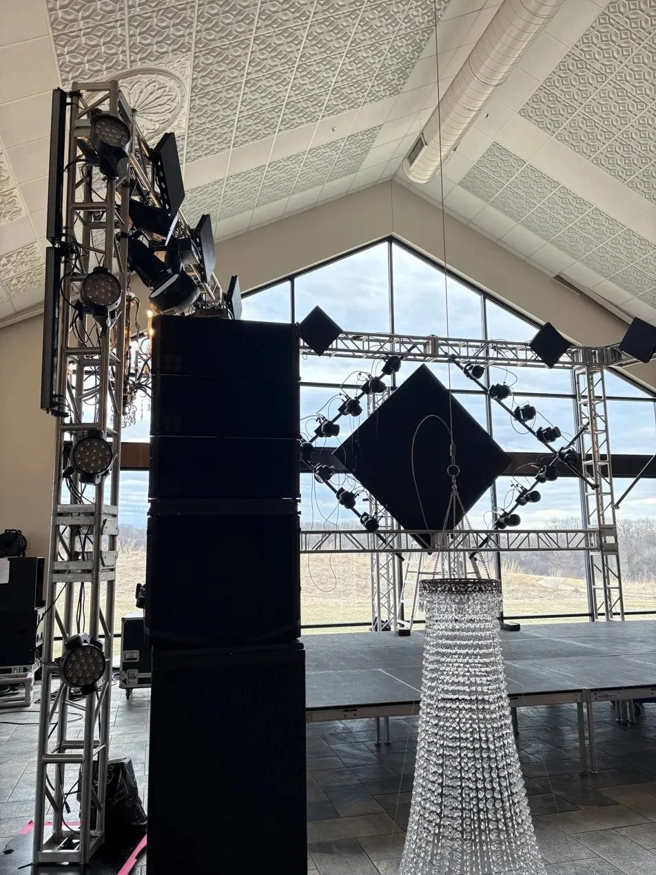 Live event stage setup with truss, line arrays, chandelier and large windows